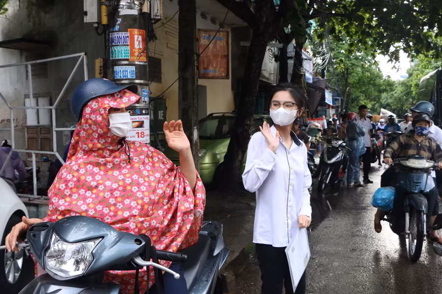 Mẹ đưa con đến trường thi khi có mưa rào đầu giờ sáng tại Trường THPT Ngô Quyền, TP Nam Định.