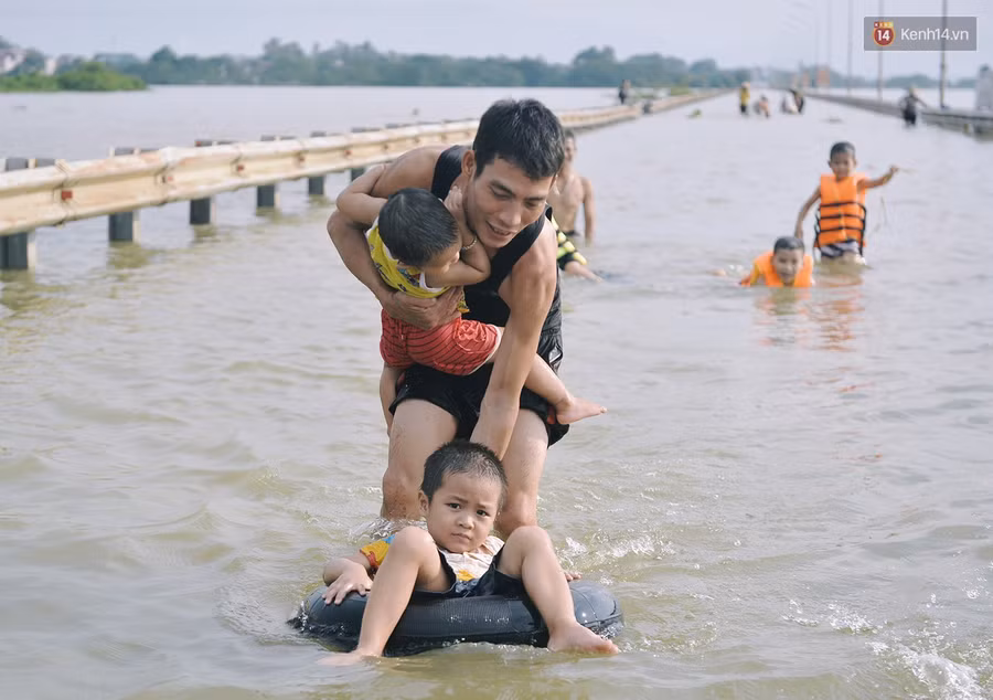 Chùm ảnh: Người lớn, trẻ nhỏ Hà Nội mặc áo phao ùa ra đường tỉnh lộ bơi lội, đánh cá sau nhiều ngày mưa ngập - Ảnh 10.