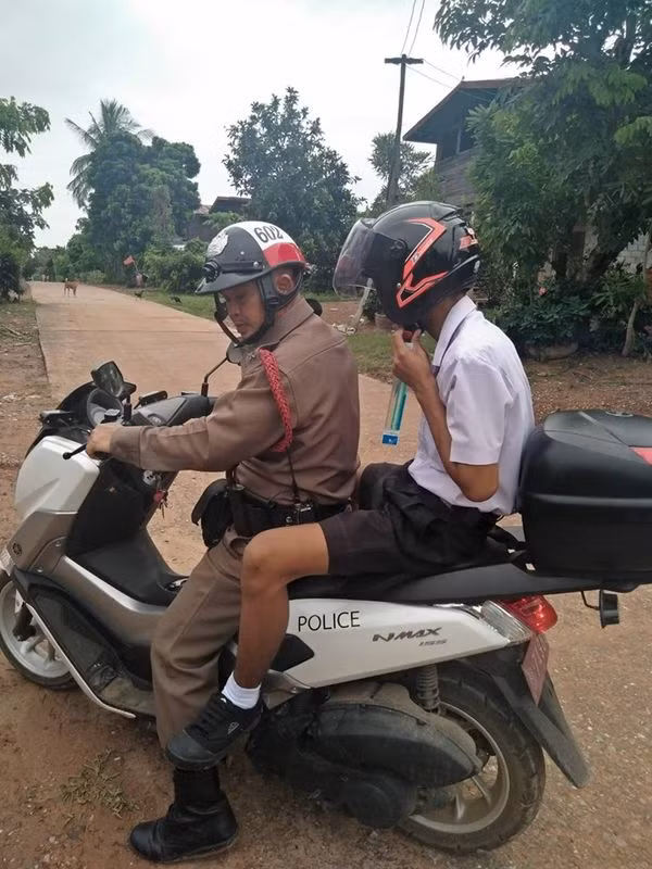 Cậu nhóc đành phải theo chú cảnh sát đến lớp.