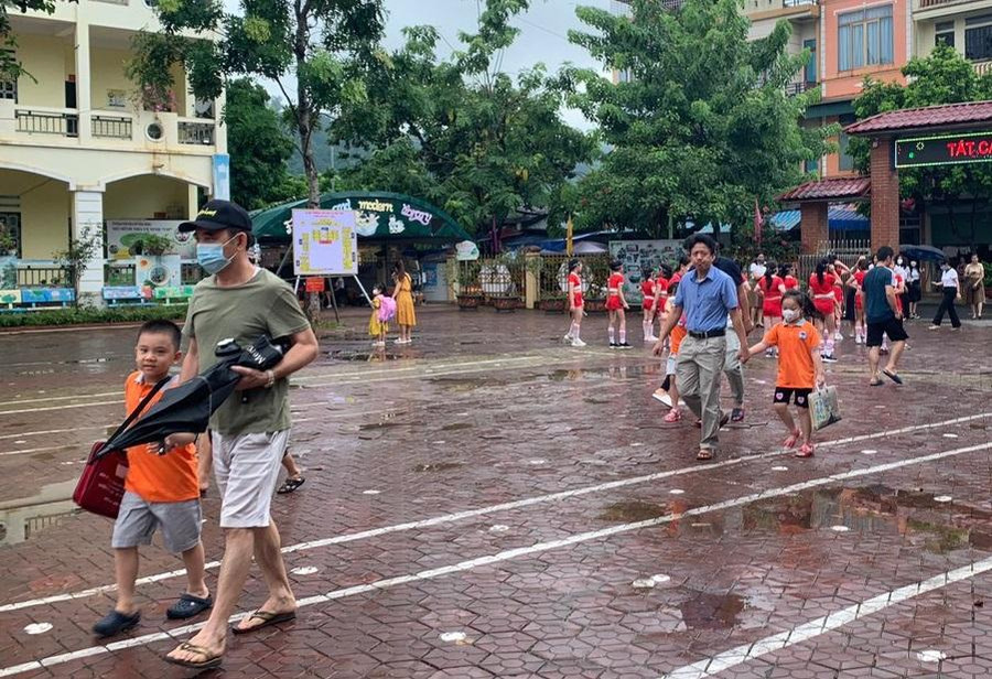 Học sinh vui vẻ khi được bố mẹ dắt tay đến trường.