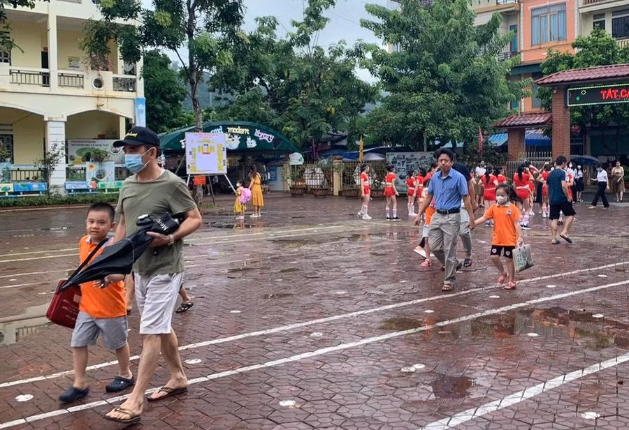 Học sinh vui vẻ khi được bố mẹ dắt tay đến trường.