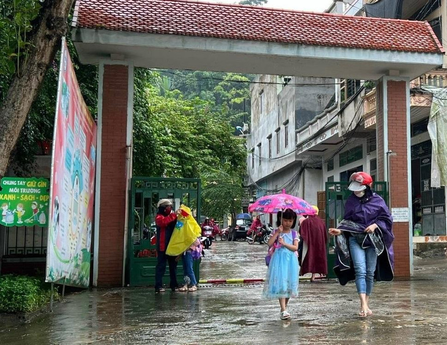Nhiều phụ huynh "đội mưa" đưa con đến trường.