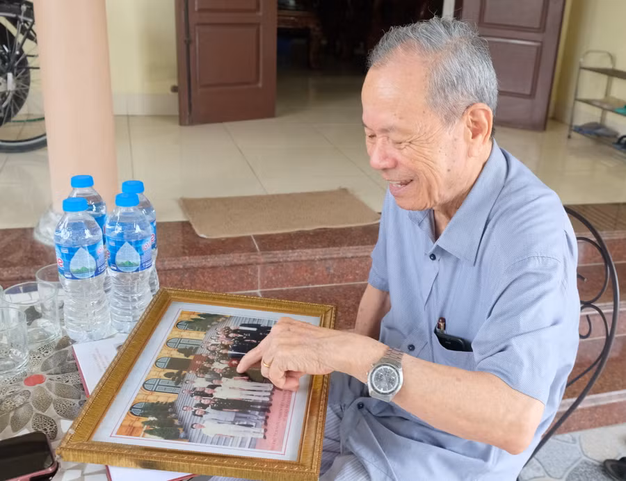 Đại tá Bùi Sáu bên tấm ảnh chụp cùng đồng đội. (Ảnh: NT).