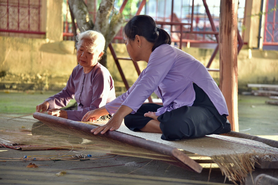 Bà Nguyễn Thị Vân cùng con gái dệt chiếu thủ công tại Đình Định Yên trước giờ diễn ra show thực cảnh.