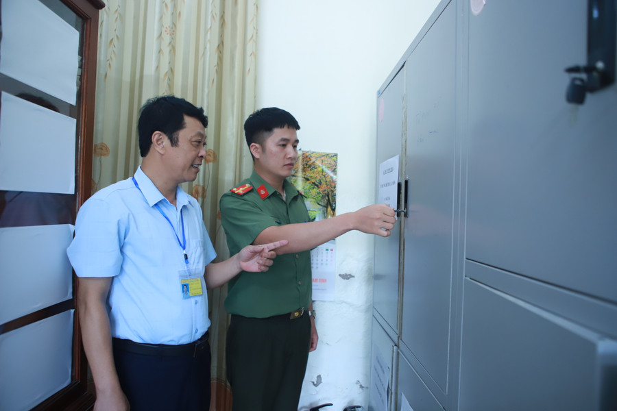 Thầy Lê Thanh Giang và cán bộ an ninh kiểm tra độ an toàn của tủ đựng đề thi, bài thi tại điểm thi Trường THPT Ngô Quyền, TP Nam Định trong sáng 26/6. Ảnh: Đình Tuệ.