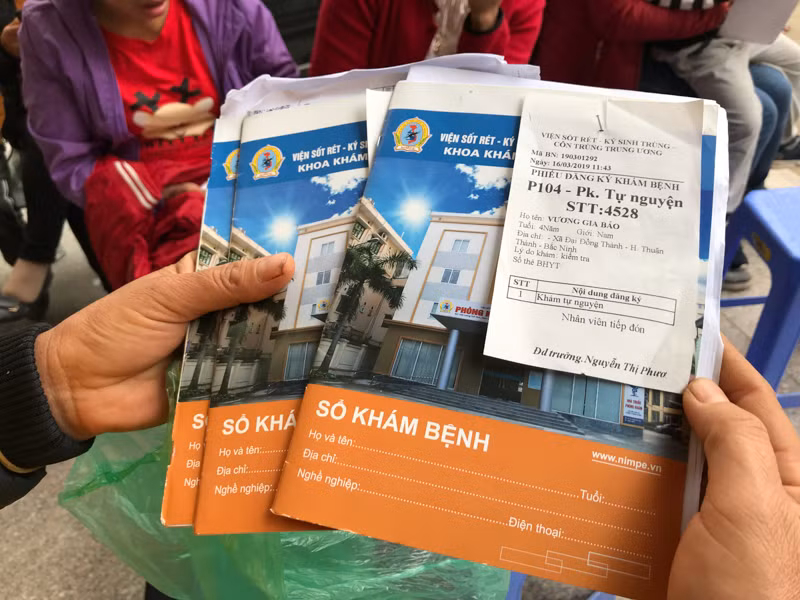 Chị Nguyễn Thị Lâm trên tay cầm 4 cuốn sổ bệnh án, trong đó có 1 cuốn sổ có nghi có nhiễm sán lợn.