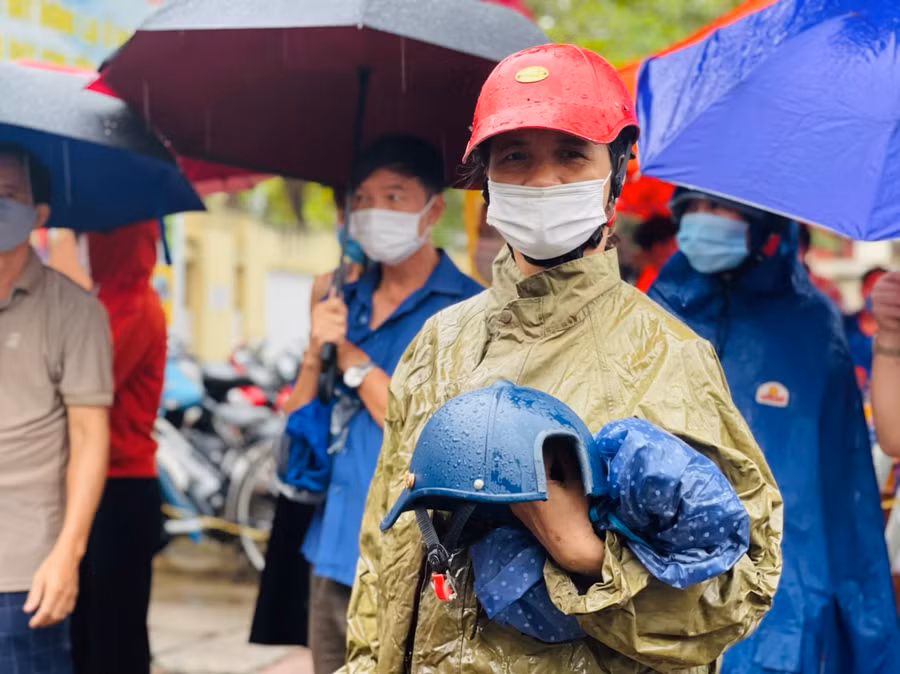 Phụ huynh "đội mưa" chờ con thi xong môn thí thứ nhất.