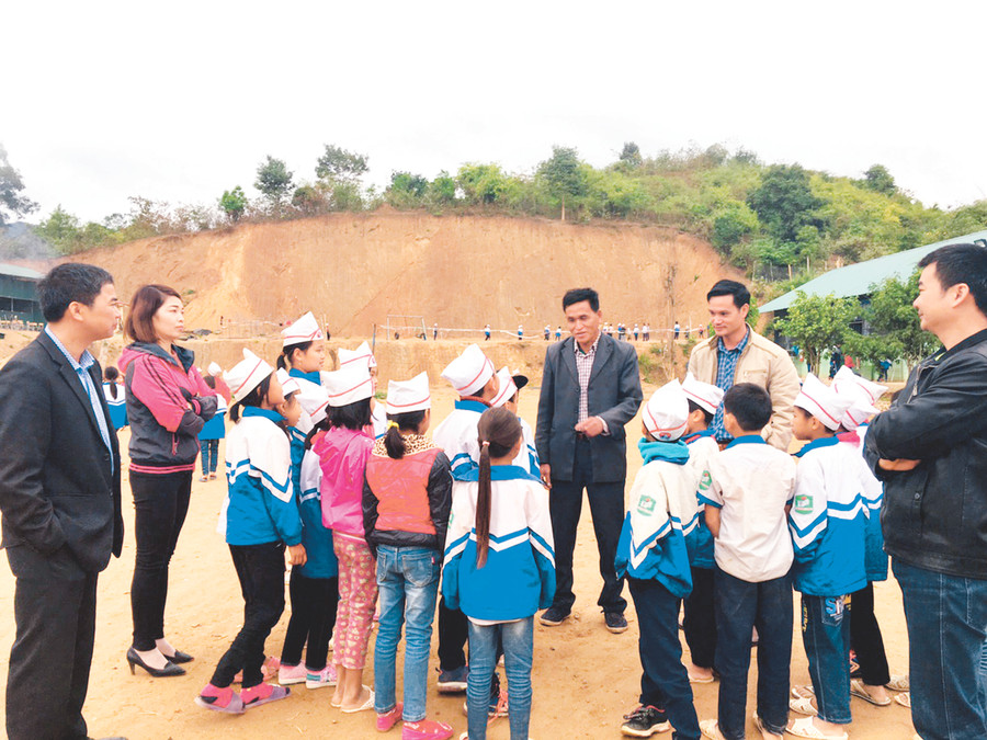 Ông Lò Văn Phúi (người đứng giữa) trò chuyện với các cháu HS tại ngôi trường do ông hiến tặng đất để xây dựng