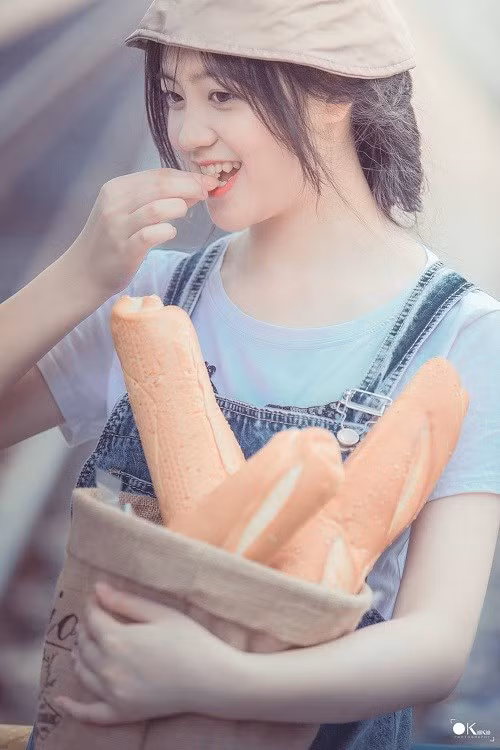 Khác với những cô bán bánh mì dạo thường thấy, ăn mặc giản dị mộc mạc và gương mặt luôn phảng phất chút lo sợ, mệt mỏi vì cuộc sống mưu sinh. Trong bộ ảnh này, 9X xinh đẹp lại hóa thân thành cô gái tay ôm ổ bánh rất đỗi hồn nhiên, khuôn mặt tươi tắn rạng ngời không chút âu lo.