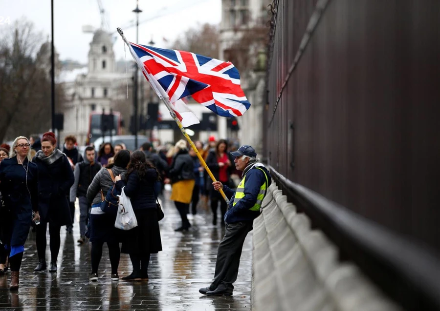 Dòng người thờ ơ đi ngang qua người đàn ông đang thể hiện sự ủng hộ đối với Brexit cũng như bà May, bên ngoài tòa nhà Quốc hội Anh hôm 16/1 