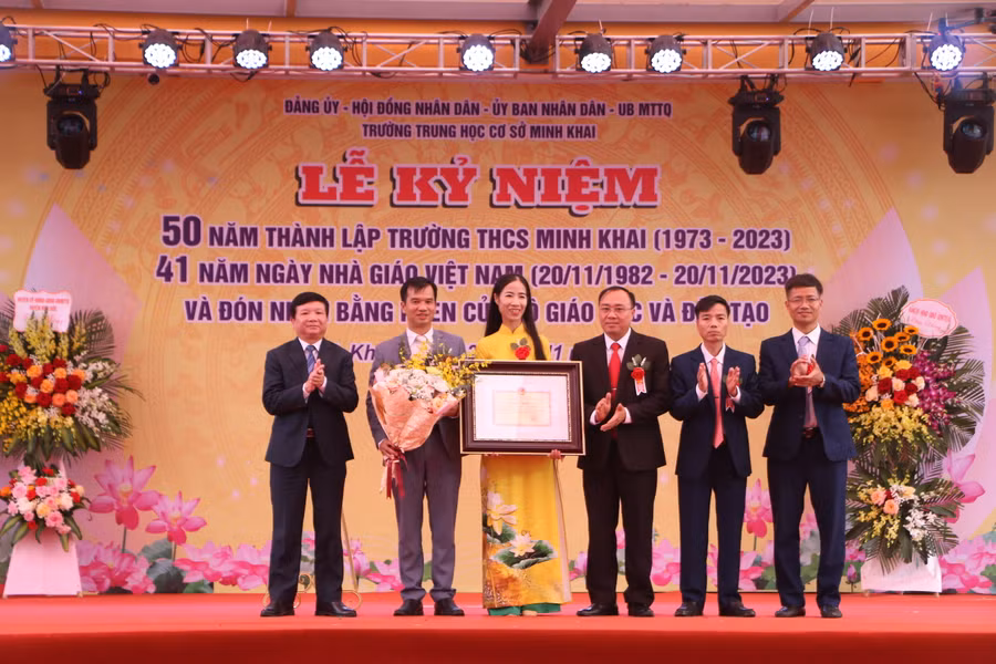 Ông Trần Văn Nghĩa (bìa trái) - Phó Bí thư thường trực Huyện ủy, Chủ tịch HĐND huyện Hoài Đức trao tặng Bằng khen của Bộ trưởng Bộ GD&amp;ĐT cho nhà trường.