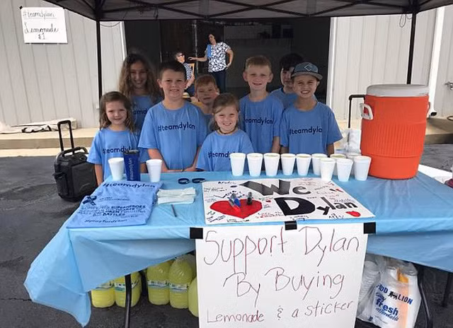 Andrew (thứ hai từ trái sang) và các bạn trong TeamDylan bán nước chanh và áo phông để cứu em trai. Ảnh: Facebook.