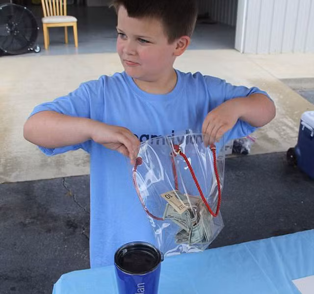 Andrew cho những tờ tiền thu được từ việc bán nước chanh vào túi và giữ cẩn thận. Ảnh: AP.