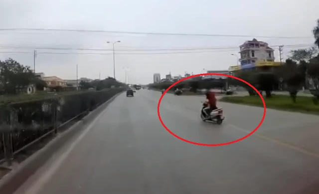  Đang chở con nhỏ, người phụ nữ buông tay lái cởi áo mưa
