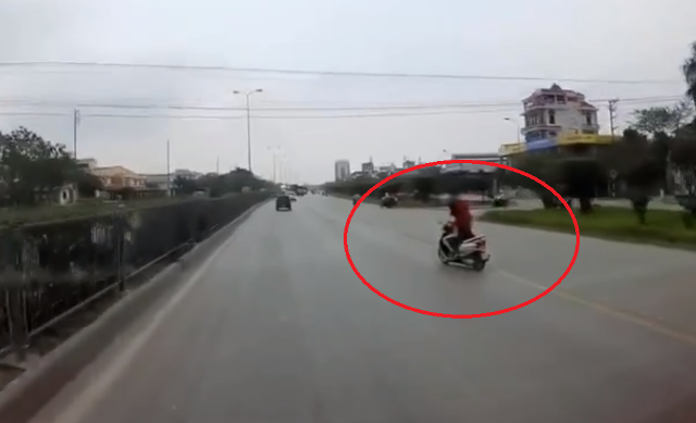  Đang chở con nhỏ, người phụ nữ buông tay lái cởi áo mưa
