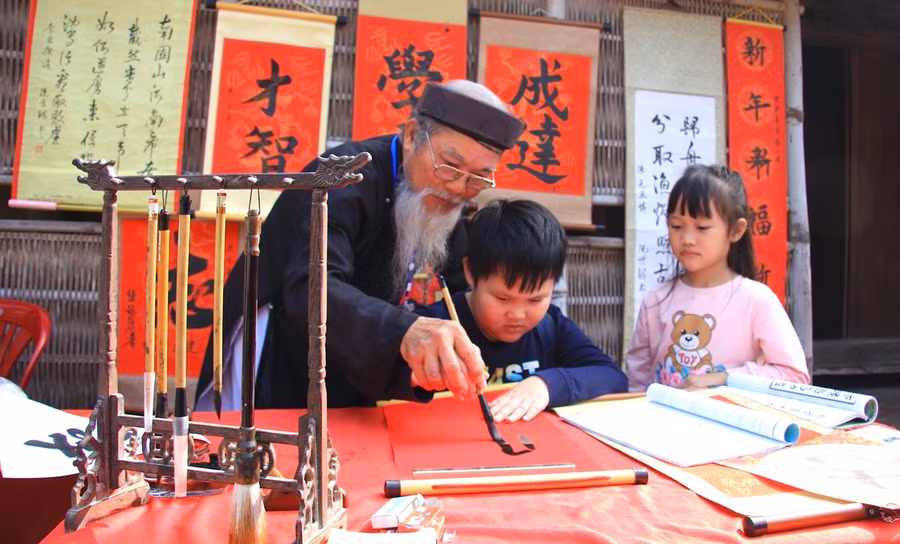 Thầy đồ Nguyễn Thiên Thuyết hướng dẫn các cháu nhỏ tập viết thư pháp.