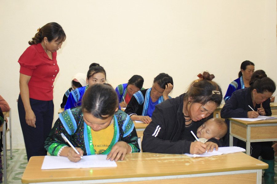 Những học viên bế con theo học lớp xóa mù chữ.