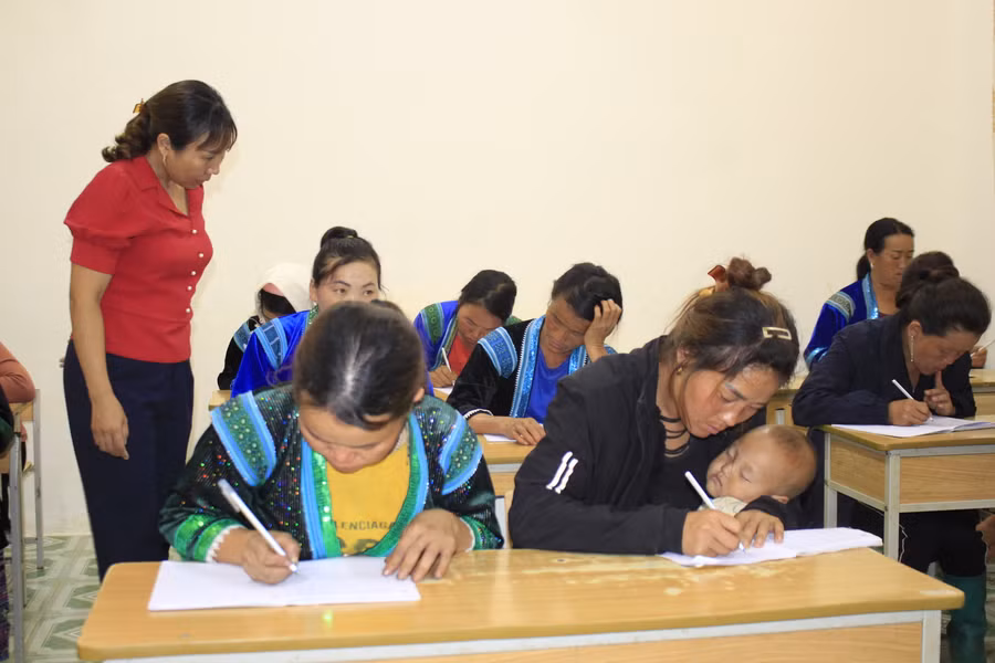 Những học viên bế con theo học lớp xóa mù chữ.