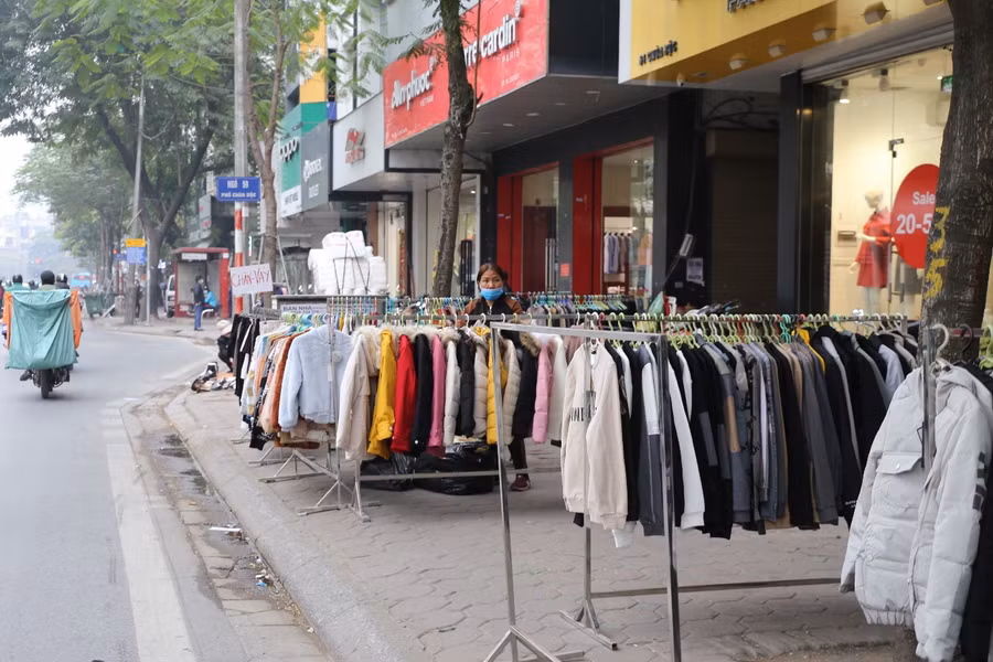 Các cửa hàng quần áo gần ngõ 59 phố Chùa Bộc ngang nhiên bày bán trên vỉa hè.