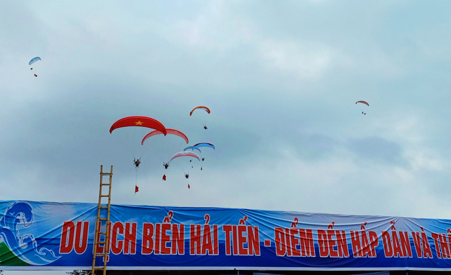 Đặc biệt, những chiếc dù lượn mang màu sắc rực rỡ, in hình của quốc kỳ Việt Nam tung bay trong gió, tạo nên điểm nhấn cho mùa du lịch biển Hải Tiến năm nay. Ảnh: LT. Đặc biệt, những chiếc dù lượn mang màu sắc rực rỡ, in hình của quốc kỳ Việt Nam tung bay trong gió, tạo nên điểm nhấn cho mùa du lịch biển Hải Tiến năm nay. Ảnh: LT.