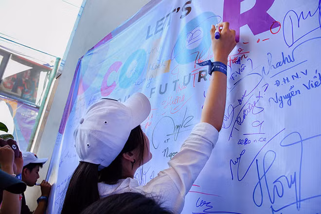 Một học sinh ký tên mình lên bảng chương trình tại trường Một học sinh ký tên mình lên bảng chương trình tại trường