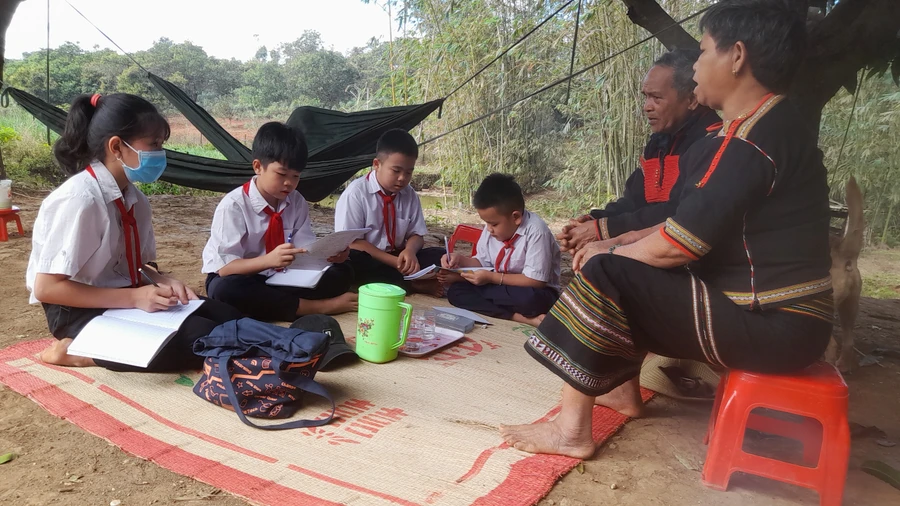 Học sinh Trường Tiểu học Bế Văn Đàn (Cư M'gar, Đắk Lắk) chăm chú ghi chép lại thông tin từ già làng để hiểu về lịch sử của buôn cách mạng Ayun. 