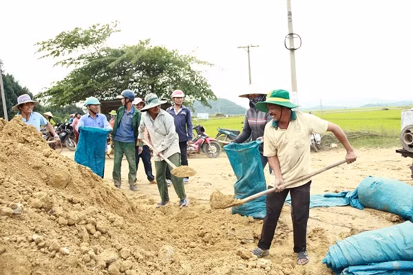 Người dân xúc đất gia cố lại đê Quảng Điền. Ảnh: Trúc Hân