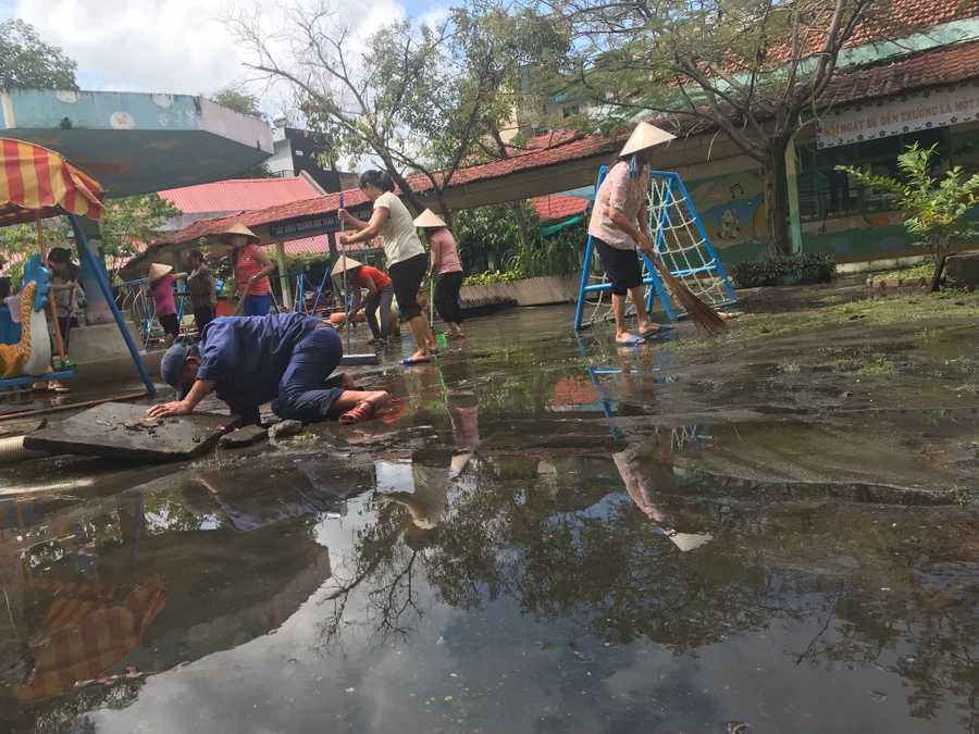 Các cán bộ giáo viên Trường Mầm non Tuổi Thơ (quận 8) đang dọn dẹp sân trường sáng 27/11