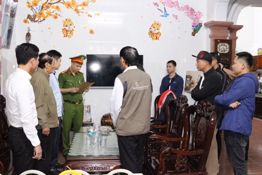 Lực lượng chức năng đọc lệnh khám xét nhà Nguyễn Tuấn Anh. (Ảnh: CANA)