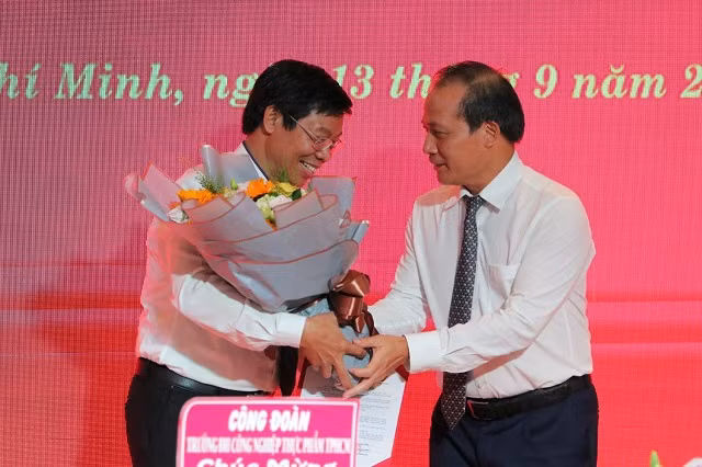 TS. Cao Quốc Hưng – Ủy viên Ban Cán sự Đảng, Thứ trưởng Bộ Công Thương (bên phải) trao quyết định bổ nhiệm và hoa chúc mừng cho tân hiệu trưởng HUFI