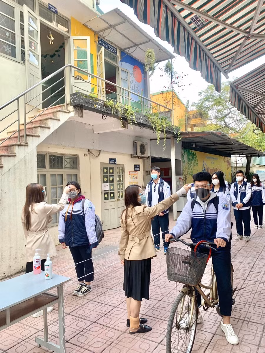 Ngay từ cổng đã phân luồng hai chiều, các em được nhân viên y tế đo thân nhiệt, sát khuẩn tay và đi theo giãn cách để vào trường.