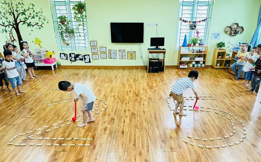 Trẻ tập dùng gậy di chuyển bóng theo đường đi riêng đã sắp sẵn.