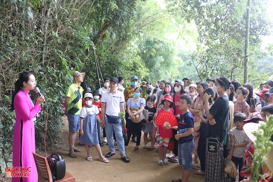 Du khách chăm chú lắng nghe thuyết minh viên của Khu di tích lịch sử quốc gia đặc biệt Kim Liên kể về cuộc đời và sự nghiệp cách mạng của Bác Hồ. Ảnh: Phạm Tâm.