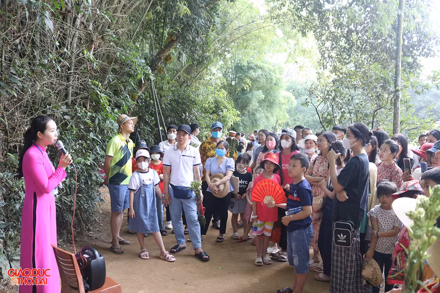 Du khách chăm chú lắng nghe thuyết minh viên của Khu di tích lịch sử quốc gia đặc biệt Kim Liên kể về cuộc đời và sự nghiệp cách mạng của Bác Hồ. Ảnh: Phạm Tâm.