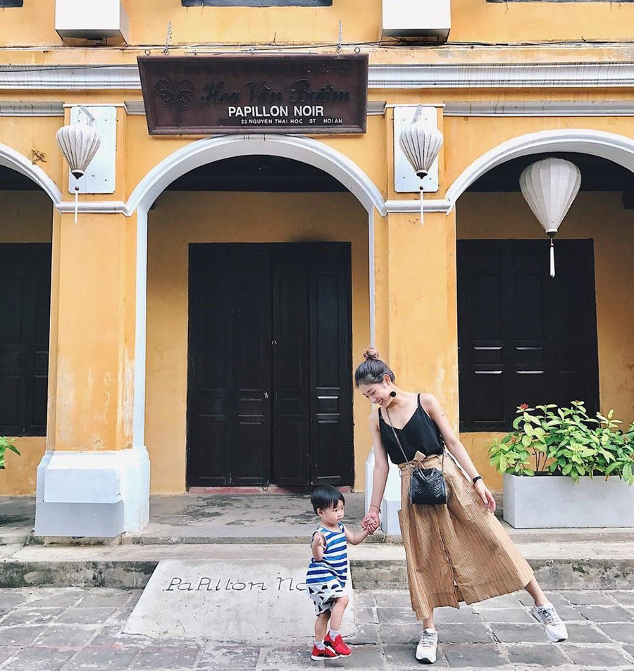 Ghé Hội An hồi hè năm ngoái, hot mom Trang Lou cũng không quên ghi lại kỷ niệm cùng bé Xoài (con trai) tại khung cảnh xưa cũ của phố cổ. Bà mẹ một con lựa chọn điểm chụp hình trước một cửa tiệm cũ lúc thưa người để có được tấm ảnh hút hàng chục nghìn lượt thích trên trang cá nhân. Vì Hội An luôn tấp nập khách du lịch, bạn nên chọn thời điểm buổi sáng từ 6-7h để có được góc chụp hình thưa bóng người. Ảnh: Trang Lou. Hoc cach
