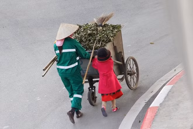  Không ở nhà chơi đùa như bao bạn cùng trang lứa, cô bé này đi theo mẹ, phụ mẹ dọn dẹp đường phố trong những ngày Tết.