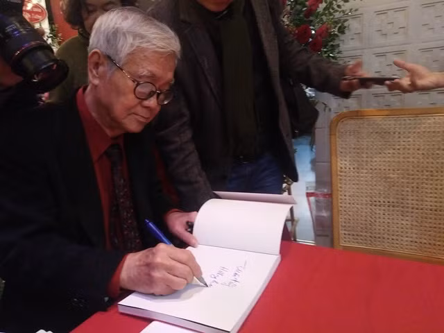 Nghệ sĩ nhiếp ảnh Hà Tường ký tặng sách ảnh "Những người muôn năm cũ". Ảnh: Bình Thanh.