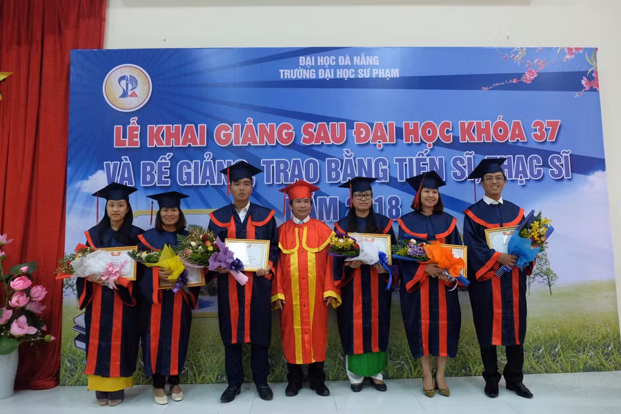 PGS.TS Võ Văn Minh - Phó Hiệu trưởng Trường ĐH Sư phạm (ĐH Đà Nẵng) trao bằng tốt nghiệp và tặng hoa chúc mừng các tân tiến sĩ, thạc sĩ.