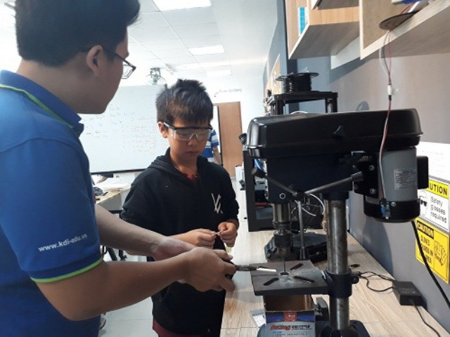 Giáo viên Đinh Thiên Phúc hướng dẫn trước HS thực hiện khoan một chi tiết của sản phẩm.