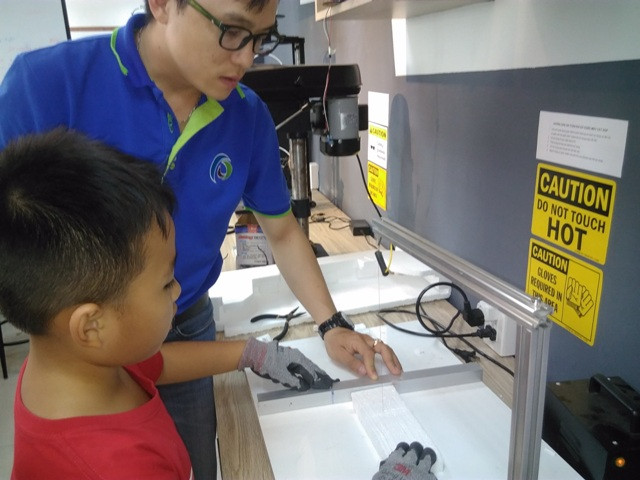 Một bạn HS đang thực hiện việc cắt miếng xốp trên dây kim loại dẫn nhiệt.