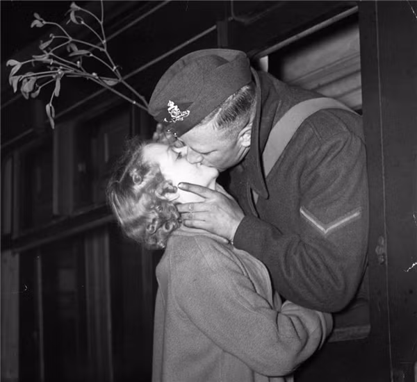 Nụ hôn tiễn biệt của người lính và người yêu trong ngày Chúa sinh ra đời vào năm 1939. Lúc chia li, chàng trai còn mang theo nhánh&nbsp;cây tầm gửi như một lời hứa hẹn cho tình yêu vĩnh hằng. (Ảnh:&nbsp;Gerry Cranham)