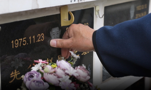 Ông Zhao chạm vào hình con trai quá cố trên tấm bia mộ anh tại Bắc Kinh. Ảnh: Sixth Tone. Ông Zhao chạm vào hình con trai quá cố trên tấm bia mộ anh tại Bắc Kinh. Ảnh:Sixth Tone.