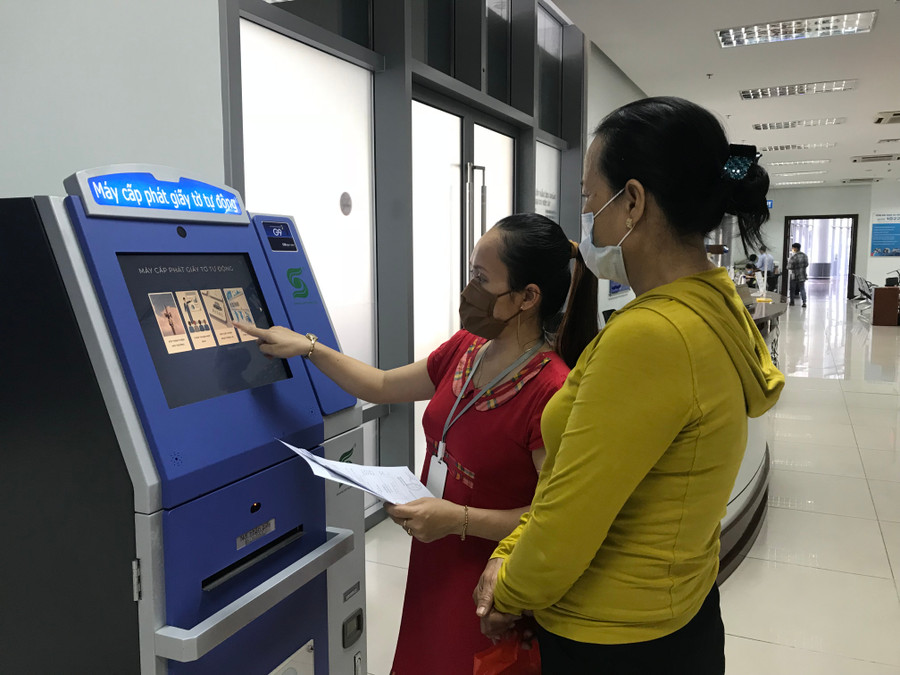 Nhân viên ở bộ phận một cửa thuộc Sở Thông tin và truyền thông TP Đà Nẵng hướng dẫn người dân và doanh nghiệp sử dụng máy phát giấy tờ tự động (KIOSK).