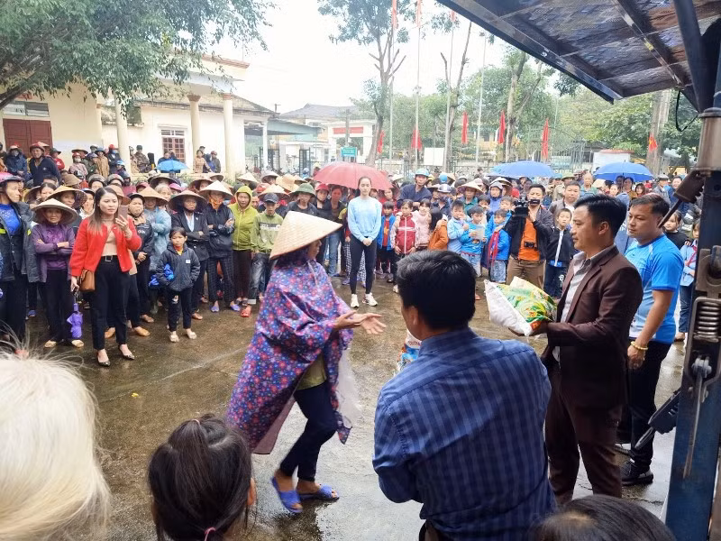 Hàng trăm người dân mặc áo mưa, cầm dù đến tận nơi để nhận những phần quá ý nghĩa.