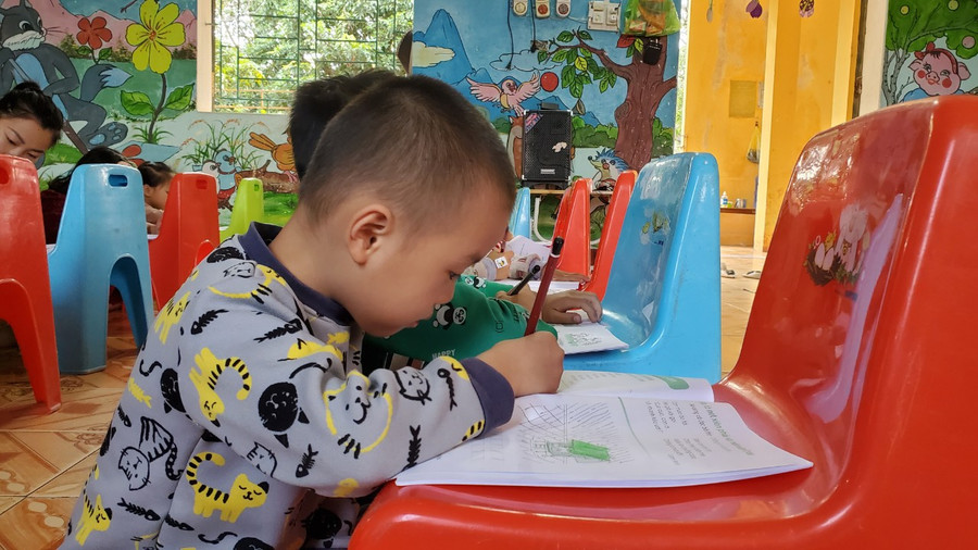 Học sinh ngồi dưới nền gạch và dùng ghế làm bàn để tập tô. (Ảnh: NT)