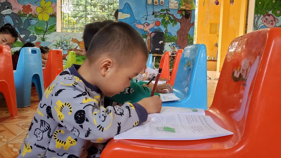 Học sinh ngồi dưới nền gạch và dùng ghế làm bàn để tập tô. (Ảnh: NT)