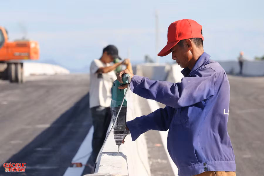 Công nhân đang hoàn thiện hệ thống an toàn giao thông như sơn kẻ đường, hộ lan, dải phân cách cứng giữa đường…