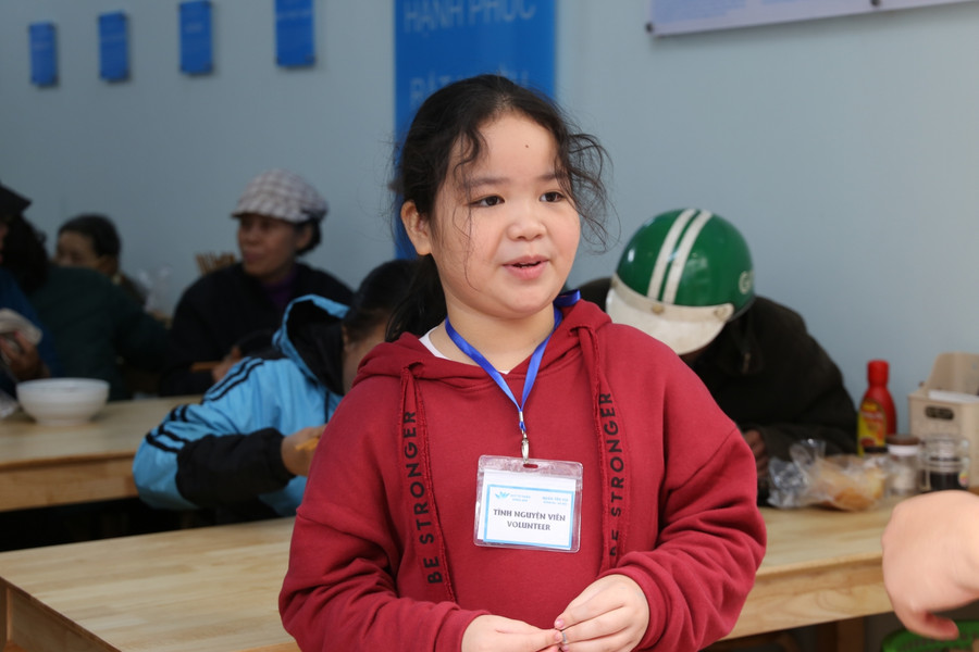 Tình nguyện viên nhí – con gái của anh Nguyễn Cao Sơn chủ quán ăn đang tiếp đón khách tại cửa.