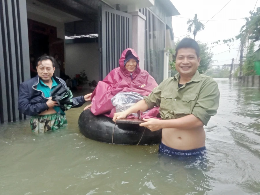 Người dân dùng phao tắm biển làm phương tiện vận chuyển trong nước lũ để đưa cụ bà đến Bệnh viện điều trị.