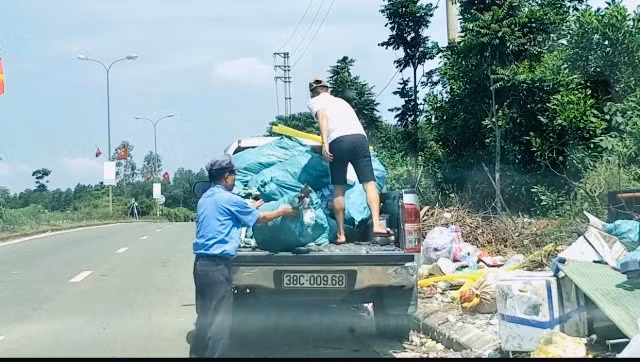 Hai người đàn ông dùng xe bán tải chở rác vứt ra đường quốc lộ.